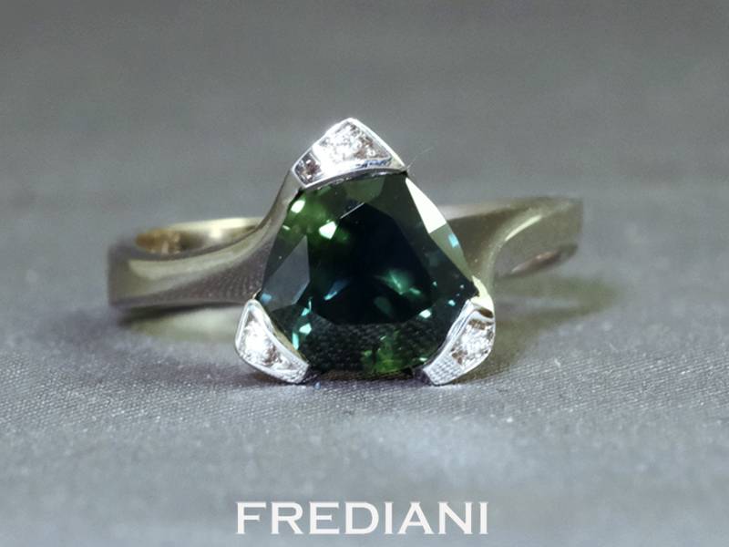 Bague en or blanc 750/000 sertie d'un saphir vert de forme troïdia certifié accompagné de 3 diamants.