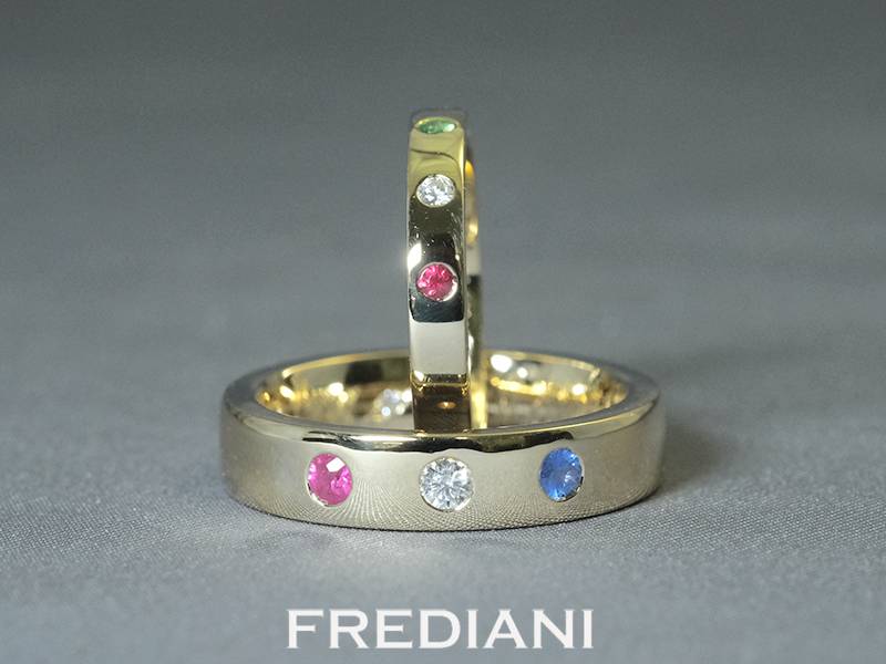 Alliances en or jaune 750/000 serties de pierres précieuses rubis, saphir bleu et diamant naturel.