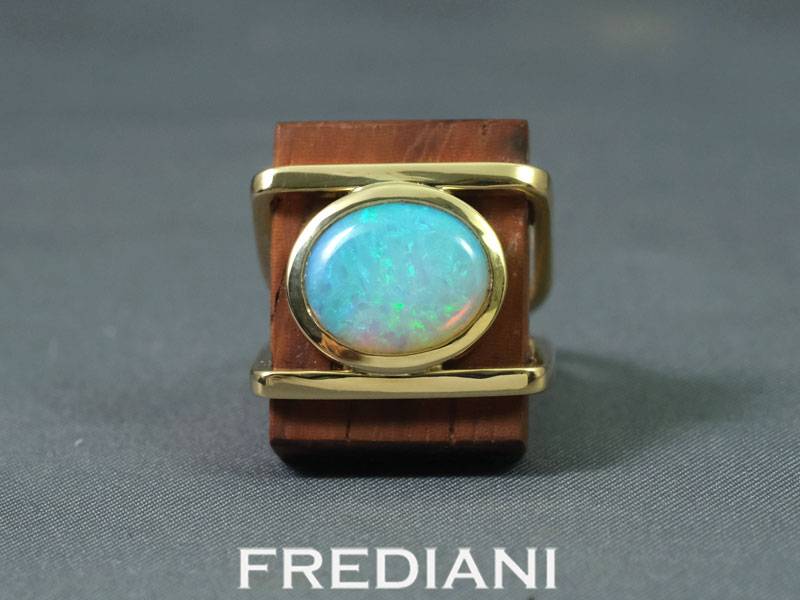 Bague en or jaune sertie d'une opale naturelle sur du bois précieux