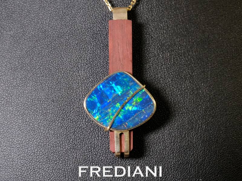 Pendentif or jaune serti d'une opale d'Australie sur du bois précieux