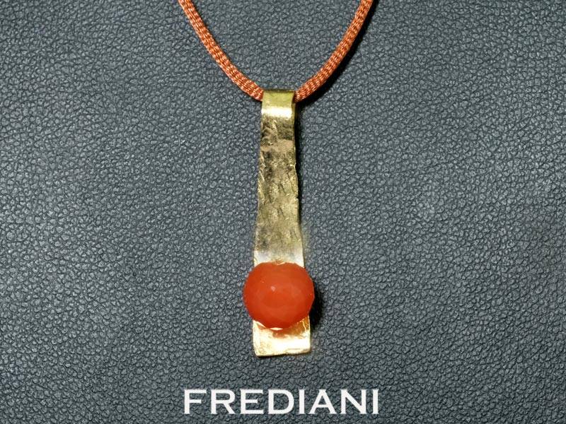 Pendentif en or jaune 750/000 martelé serti d'une boule en pierre de lune rouge facettée.