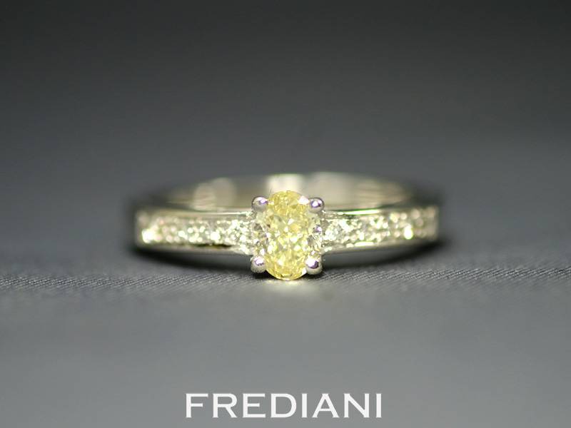 Bague en or blanc sertie d'un diamant jaune et entouré de 10 diamants blancs