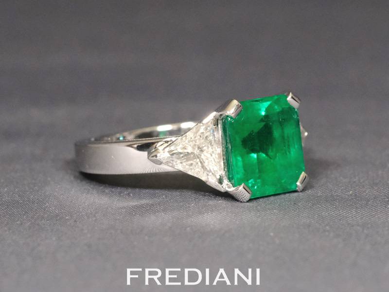 Bague en or blanc sertie d'une très belle émeraude carrée et deux diamants triangles