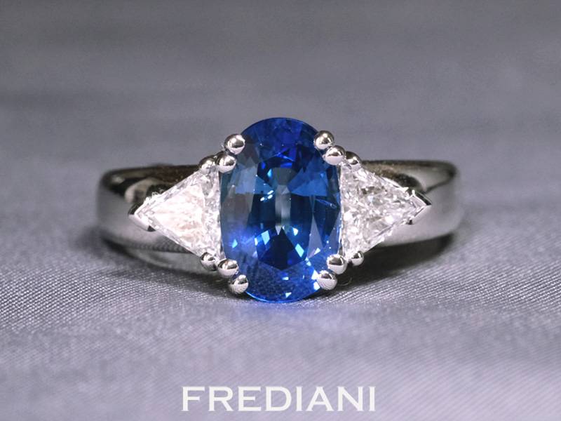 Bague en or blanc palladié 750/000 sertie d'un très beau saphir bleu entouré de deux diamants troïdias naturels.