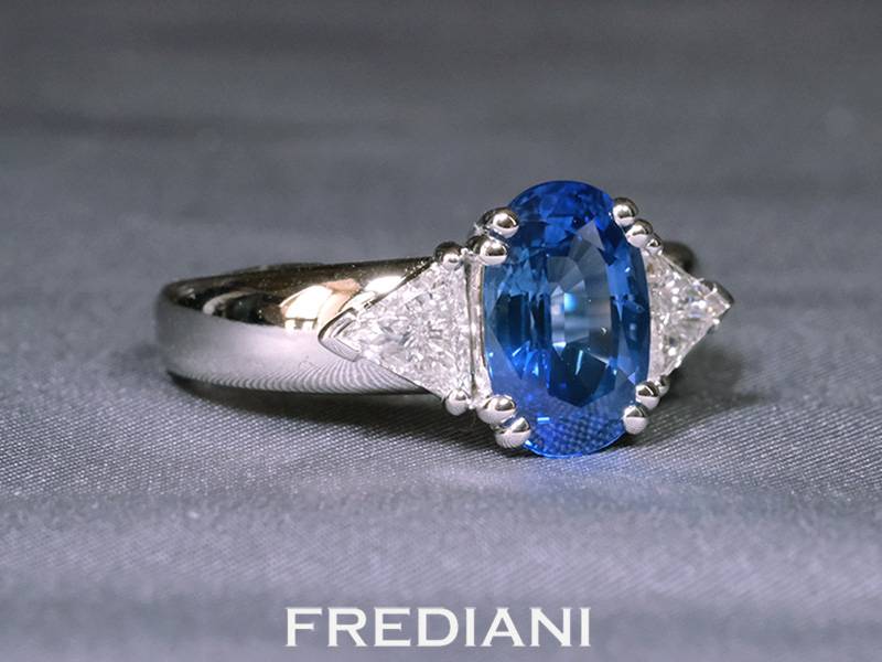 Bague en or blanc palladié 750/000 sertie d'un très beau saphir bleu entouré de deux diamants troïdias naturels.