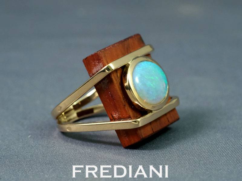 Bague en or jaune sertie d'une opale naturelle sur du bois précieux