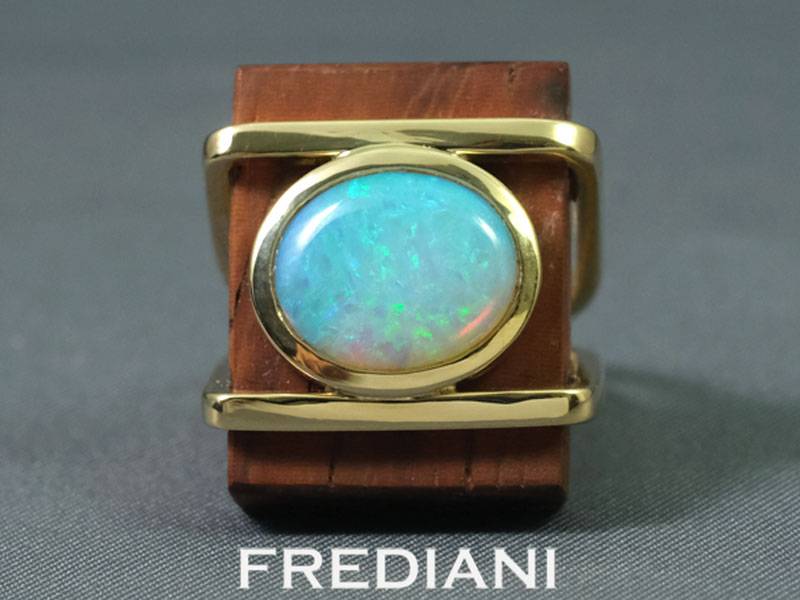 Bague en or jaune sertie d'une opale naturelle sur du bois précieux