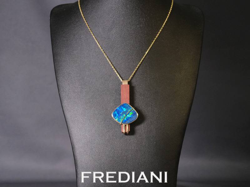 Pendentif or jaune serti d'une opale d'Australie sur du bois précieux