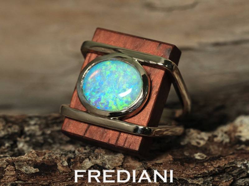 Bague en or jaune sertie d'une opale naturelle sur du bois précieux