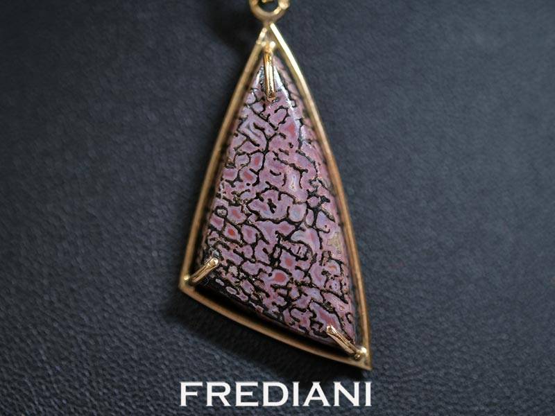 Pendentif en or jaune 750/000 serti d'un cabochon en os de dinosaure pétrifié.