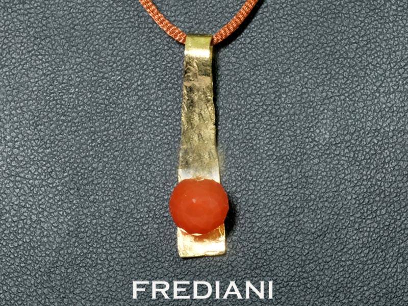 Pendentif en or jaune 750/000 martelé serti d'une boule en pierre de lune rouge facettée.