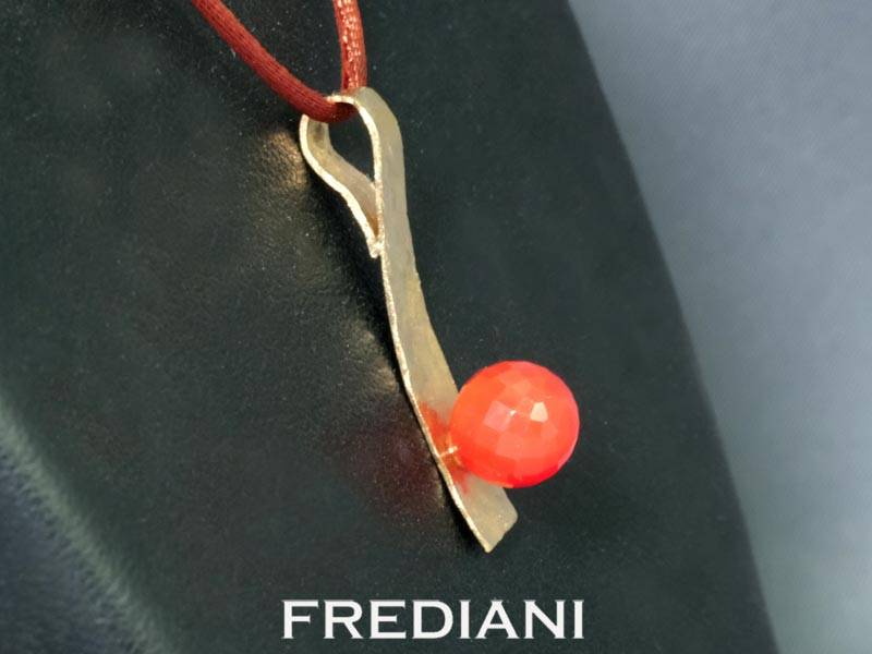 Pendentif en or jaune 750/000 martelé serti d'une boule en pierre de lune rouge facettée.
