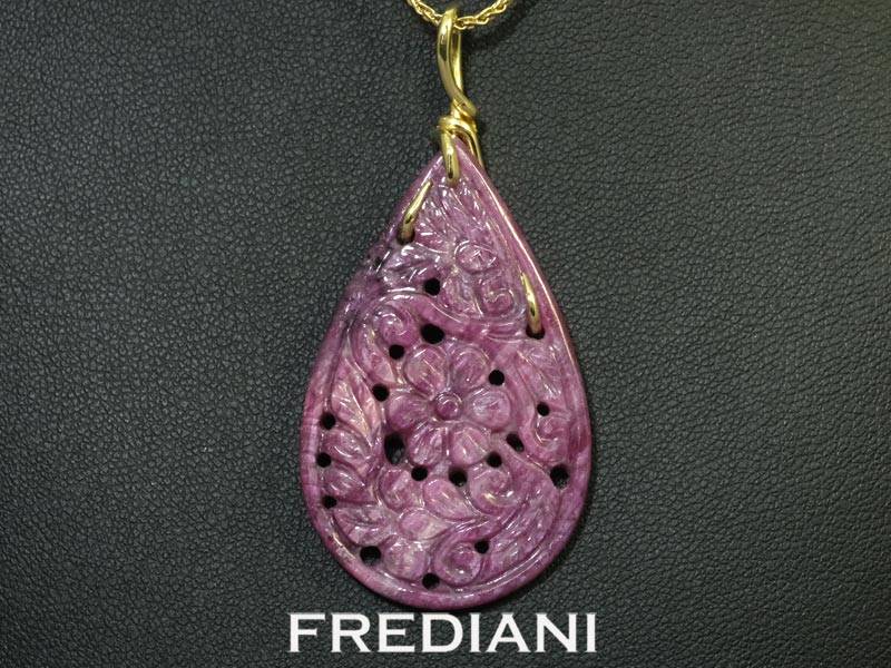 Pendentif en or jaune 750/000 serti d'un magnifique rubis ornemental finement sculpté.