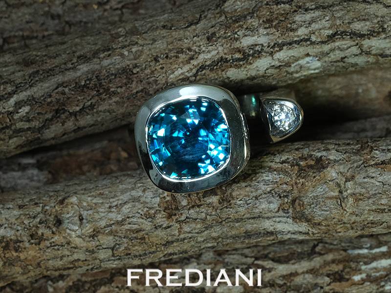 Bague en or blanc 750/000 sertie d'un magnifique zircon bleu coussin et accompagné d'un diamant rond naturel.