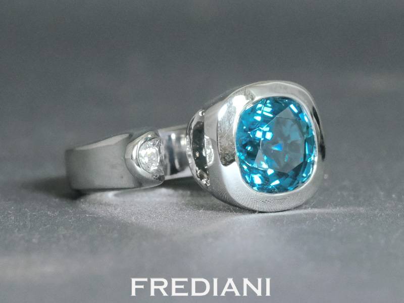Bague en or blanc 750/000 sertie d'un zircon bleu coussin accompagné d'un diamant rond