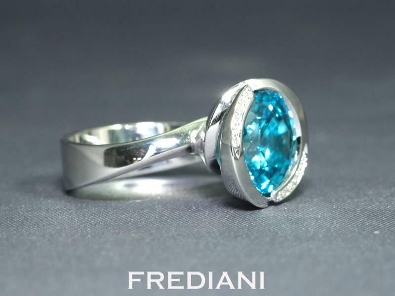 Bague en or blanc 750/000 sertie d'un magnifique zircon bleu rond et accomopagné de 12 diamants naturels.