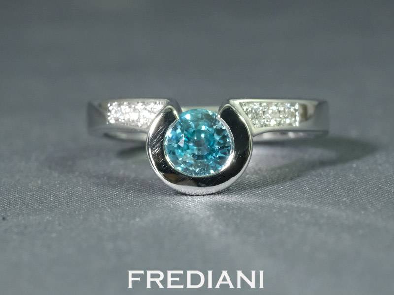 Bague en or blanc 750/000 sertie d'un zircon bleu rond et 6 diamants naturels.